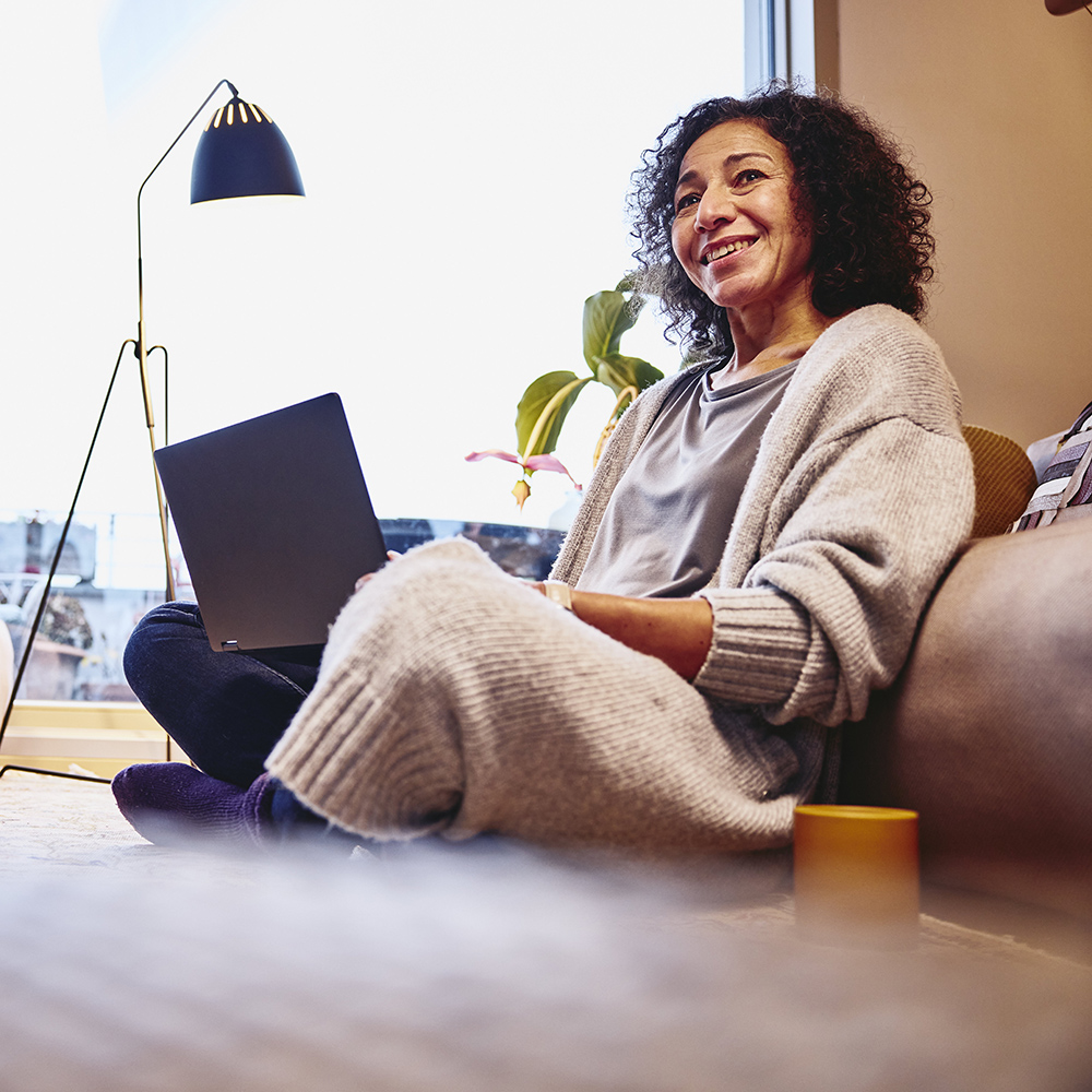 kvinne som sitter i sofa med laptop klar til å registrere cv