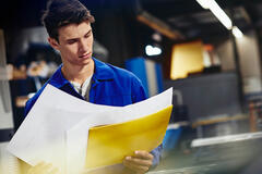 male looking down at papers in a production site/factory