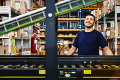 Smiling male standing behind a conveyor belt