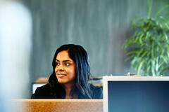 Kvinne ved pulten sin, bak datamaskinen