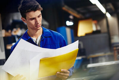 male looking down at papers in a production site/factory
